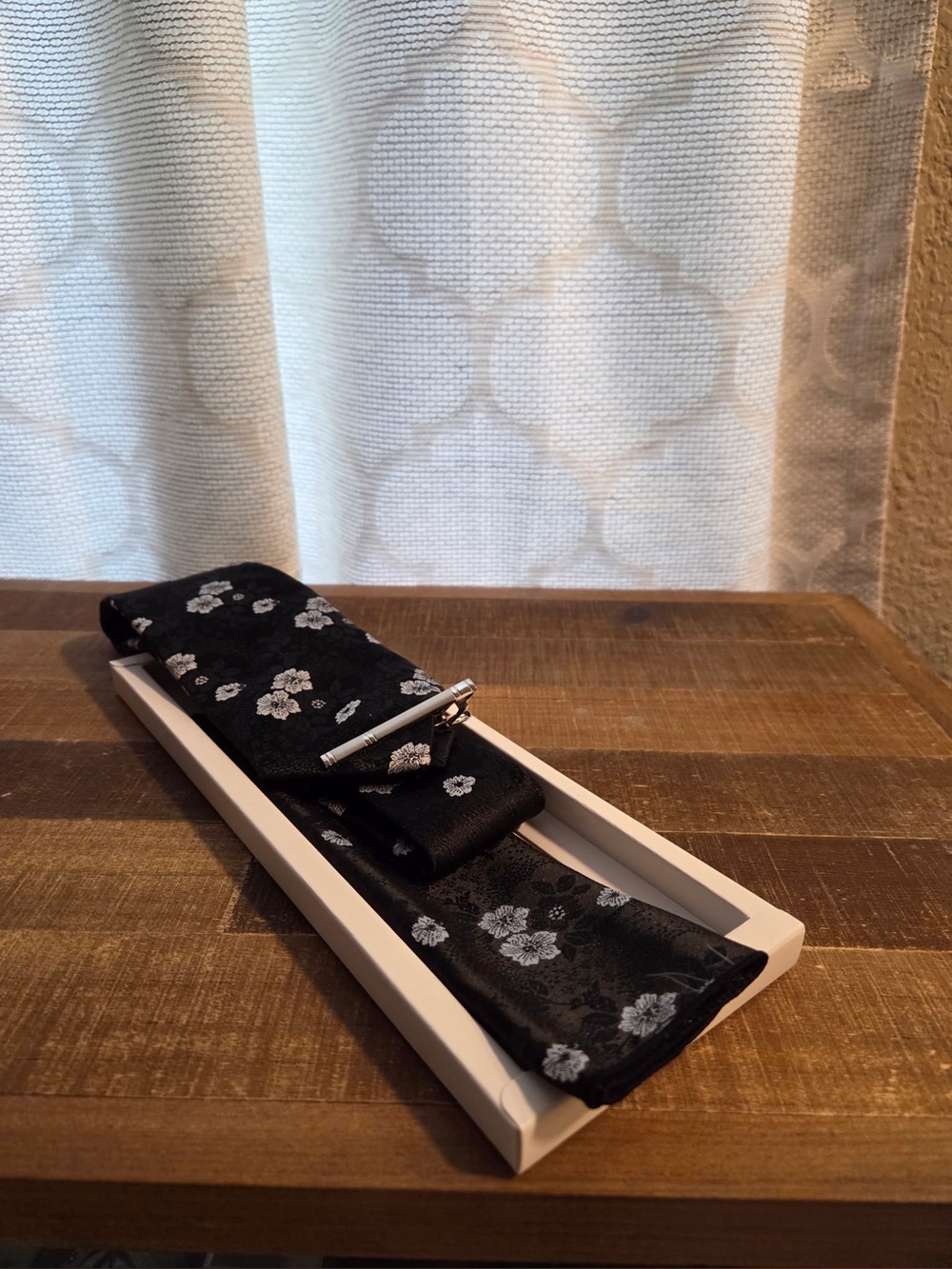 floral necktie with a black and white print.
Necktie, pocket square, tie clip